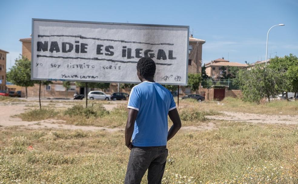 Agustín Ndour, senegalés que trabaja como monitor de encuadernación en Cáritas en Granada, ante la pintada que se alza en medio de la Zona Norte.