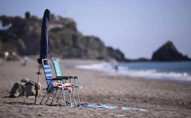 Dos sillas de playa y una sombrilla esperando a sus dueños en la playa de Almuñécar, donde en verano no cabrá ni un alfiler. 
