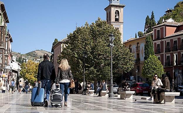 Dos turistas tiran de sus maletas por Plaza Nueva.