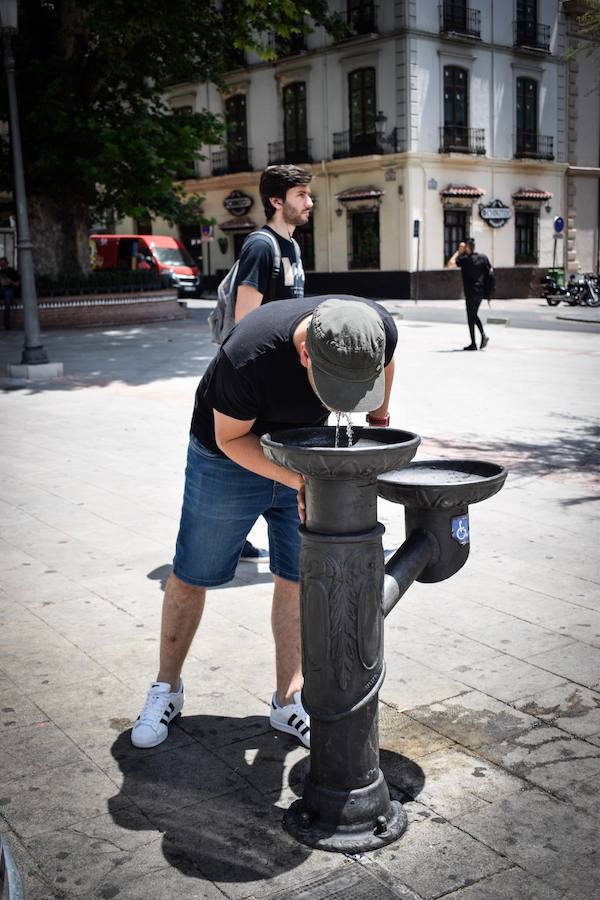 Granadinos y visitantes se las apañan en las calles para no sufrir mucho el enorme calor de estos días
