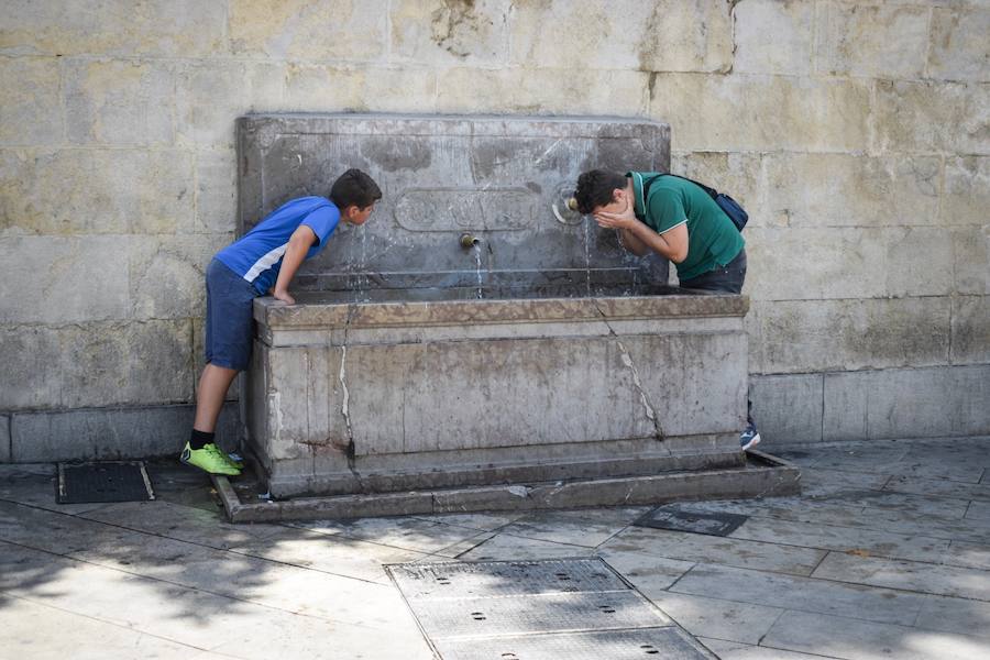 Granadinos y visitantes se las apañan en las calles para no sufrir mucho el enorme calor de estos días