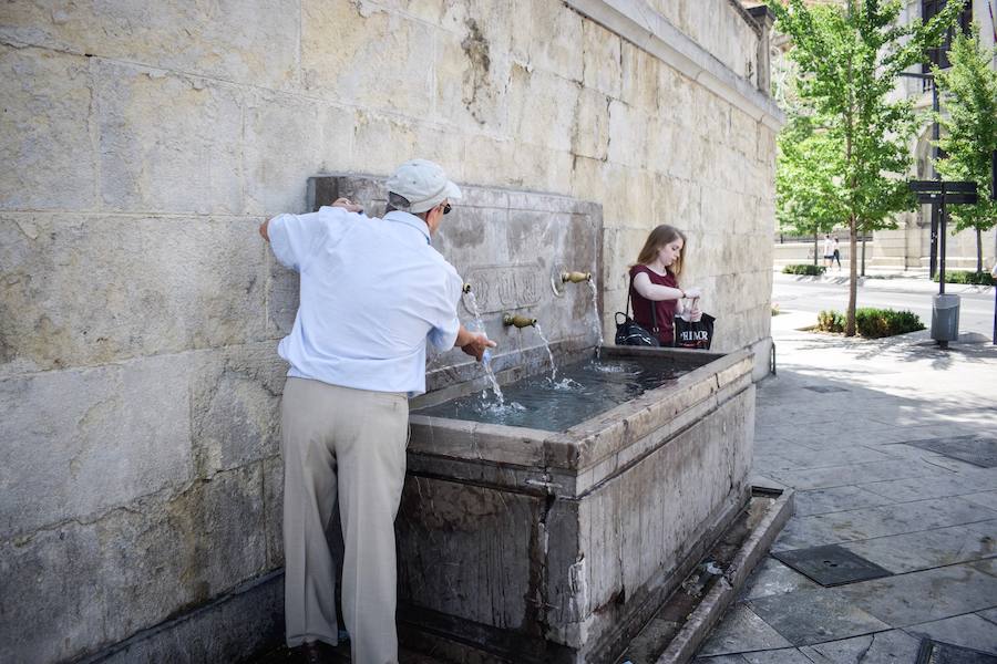 Granadinos y visitantes se las apañan en las calles para no sufrir mucho el enorme calor de estos días