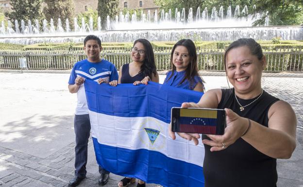 Migrantes de Nicaragua y Venezuela posan con banderas de sus países en los Jardines del Triunfo, en la capital granadina