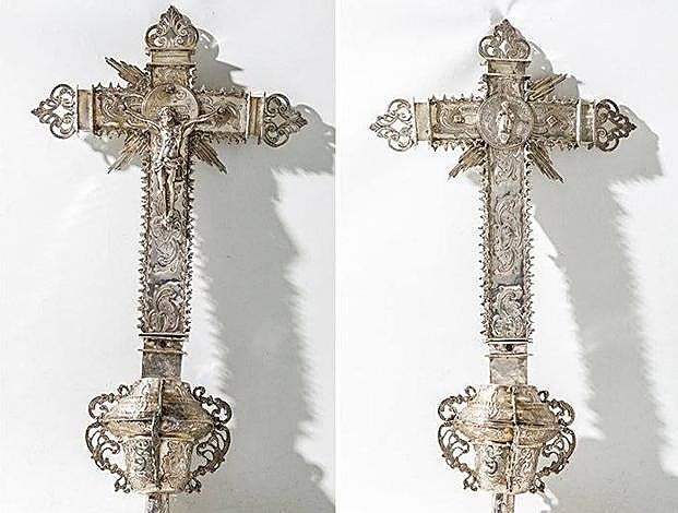 Cruz latina de brazos rectos con decoración de rocalla y volutas de acanto, y greca de crestería en el borde.