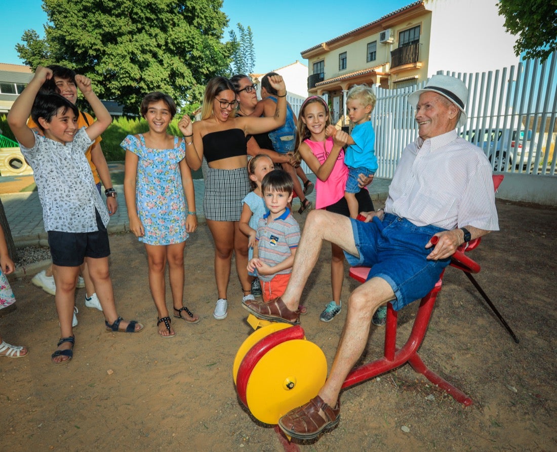 Un grupo de niños anima a un mayor que hace ejercicio en un parque de Vegas del Genil.