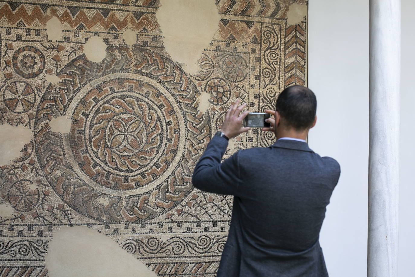 Visitante toma una foto al mural romano del Museo Arqueológico de Granada.