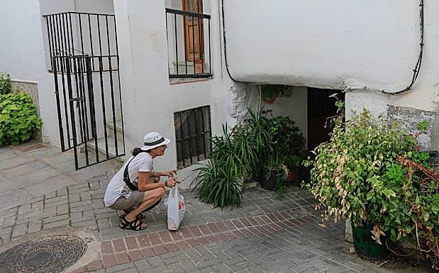 Una turista se asoma por debajo de un tinao para ver dónde conduce la calle. :