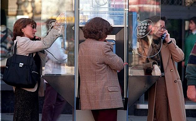 Tres mujeres hablan por teléfono en una cabina