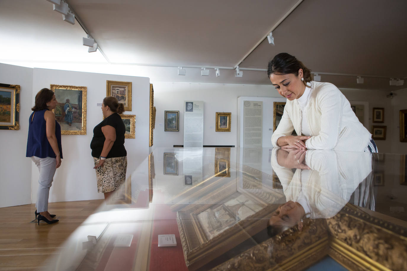 Visitantes observan los cuadros que componen la exposición.