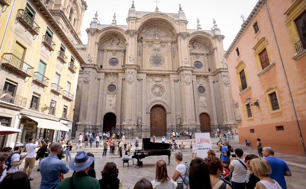 Una joven, rodeada de turistas, toca en el piano colocado en la plaza de las Pasiegas.