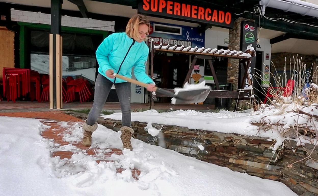 Ana limpia la nieve que cubre la acera de su negocio