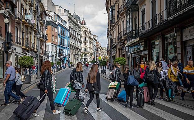 Un grupo acarrea sus carritos por la calle Reyes Católicos.