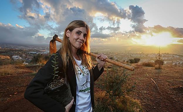 Beatriz Sánchez, fundadora de Operación Encina, posa con su azada y un plantón en el monte de Huétor Vega (Granada) donde crece su bosque.