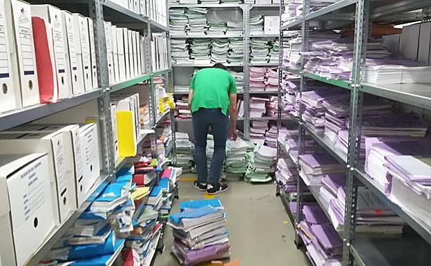 Un funcionario coge un expediente del suelo en el archivo del juzgado de lo Mercantil. 