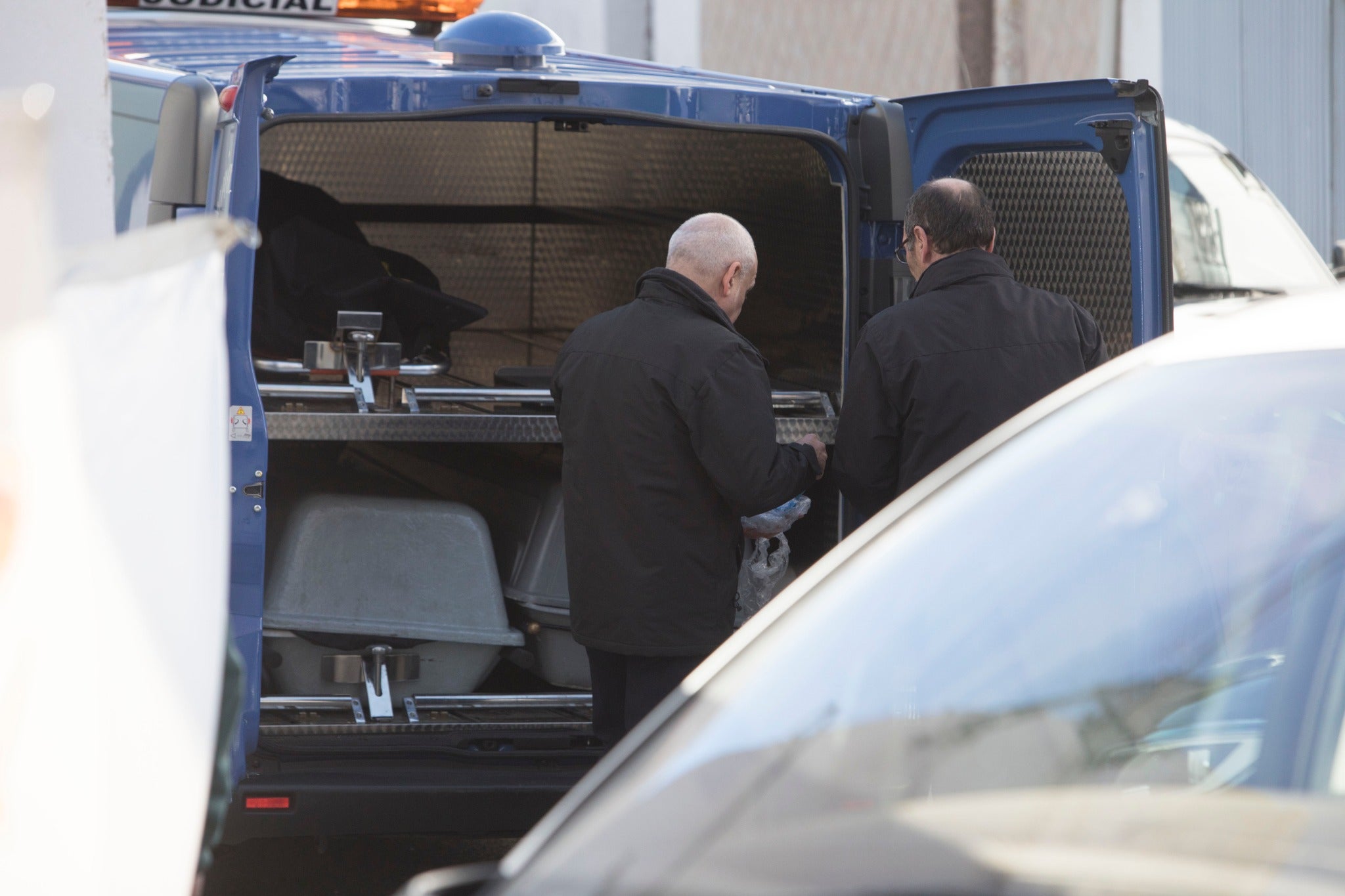 Miembros de la funeraria proceden a guardar uno de los féretros en el vehículo.