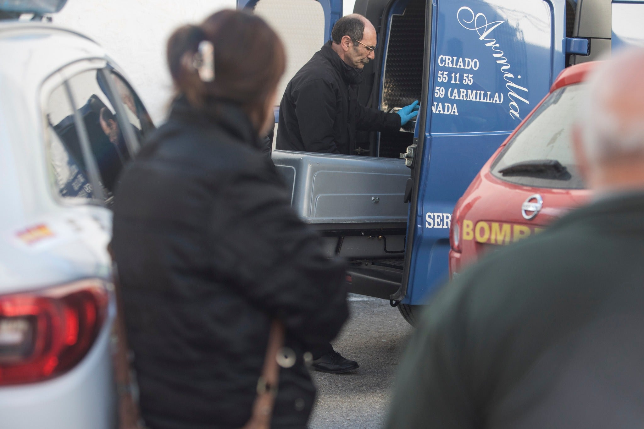 Miembros de la funeraria proceden a guardar uno de los féretros en el vehículo.