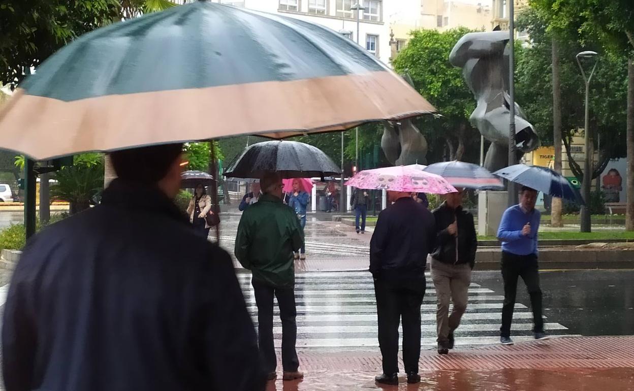 Viandantes cruzan un paso de peatones bajo la lluvia en la capital. 