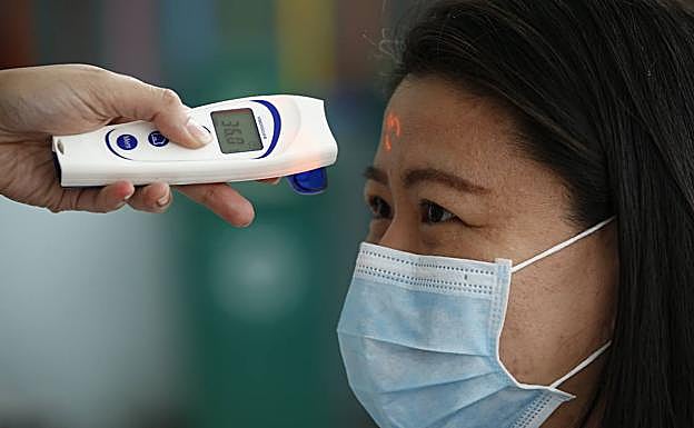 Una mujer se somete a un chequeo de la temperatura corporal que detecta el coronavirus.