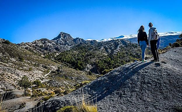 Una pareja observa los arenales dolomíticos con la cumbre del Trevenque y Sierra Nevada al fondo 