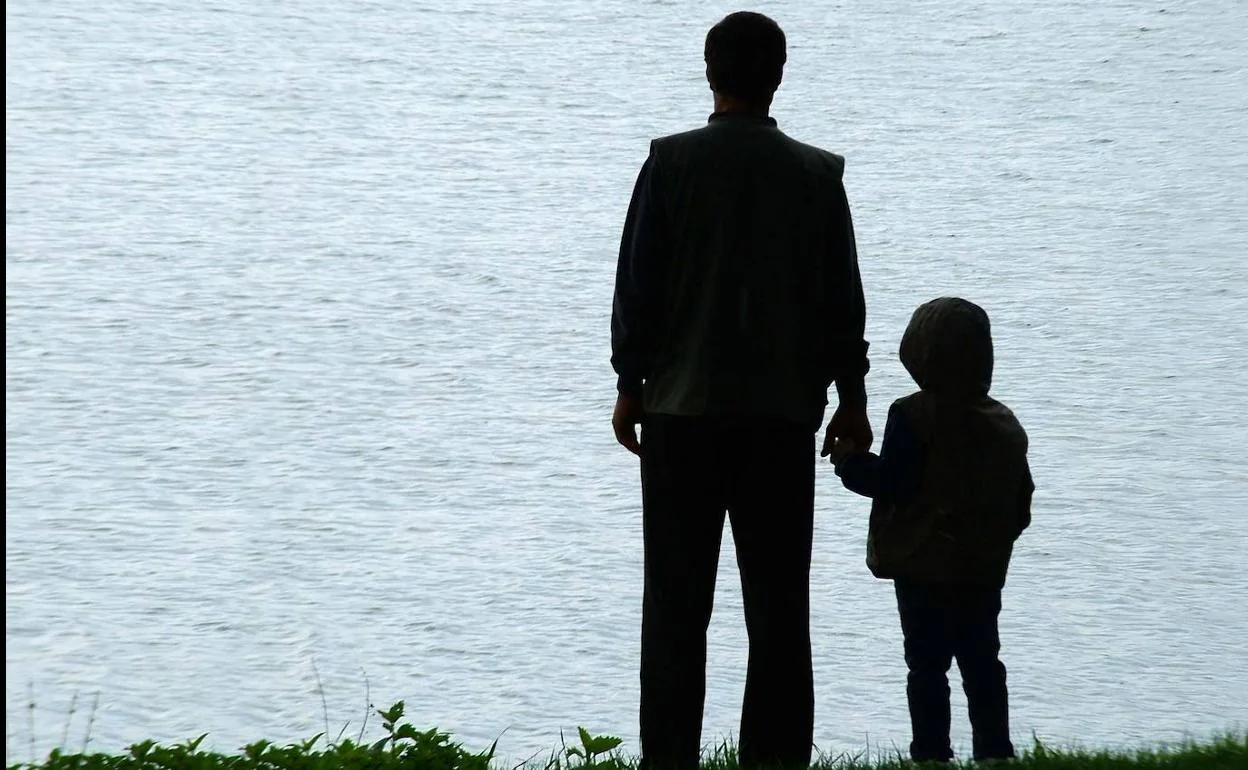 Un padre, con su hijo, contempla el mar en la Costa. 