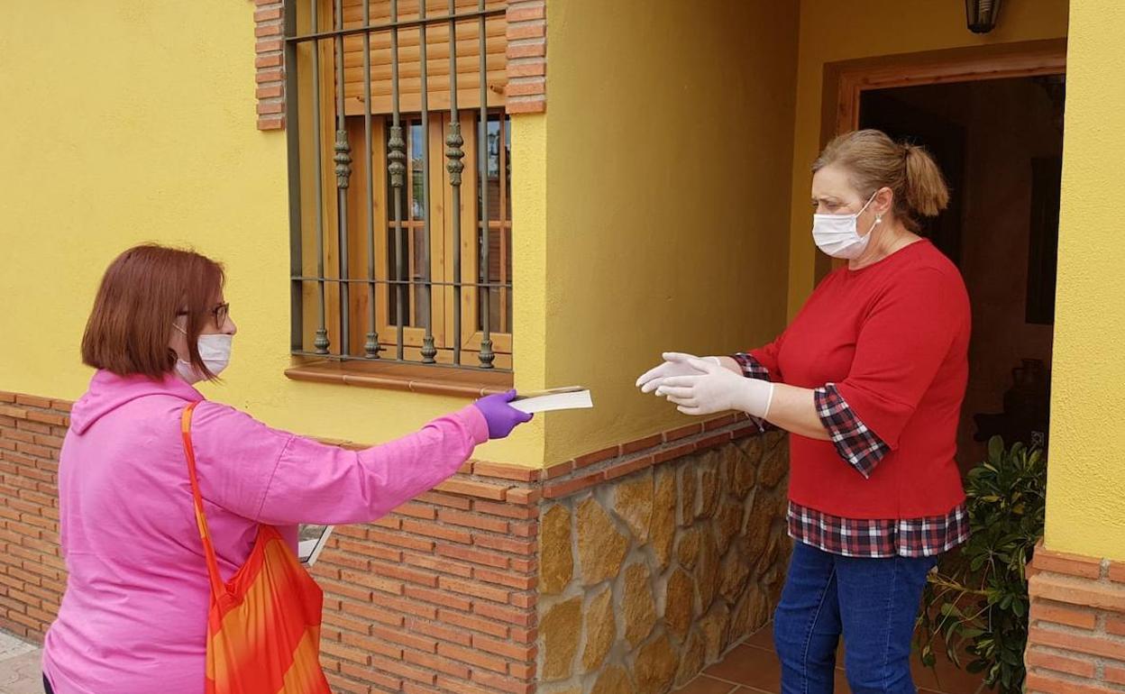 Una trabajadora municipal entrega un libro a una vecina.