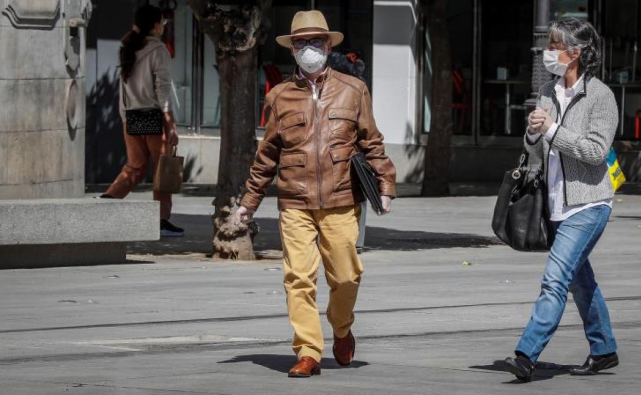 Dos personas se cruzan por la calle ataviadas con mascarillas.