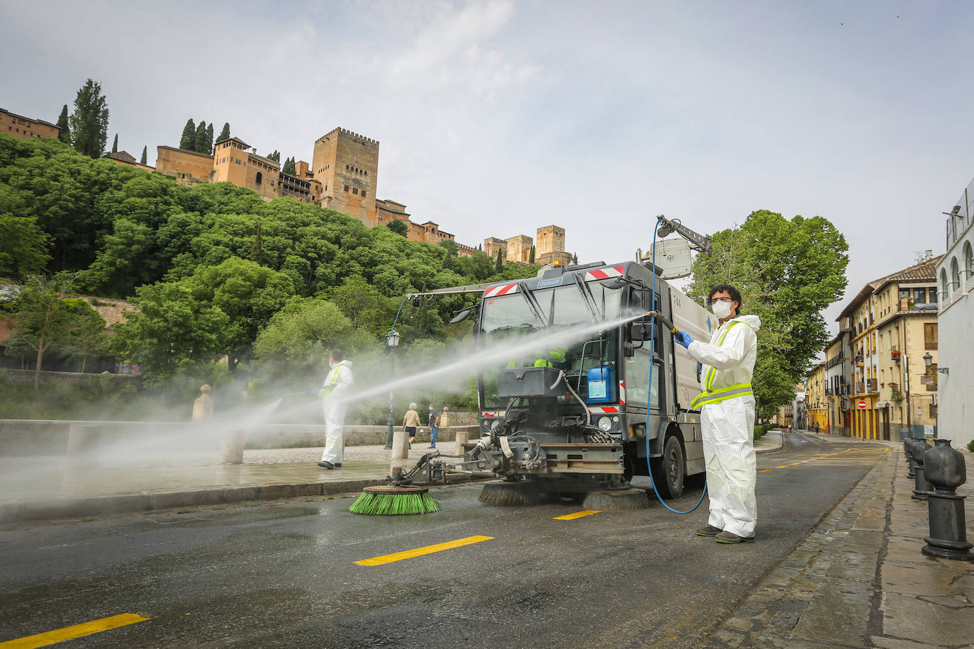 Operarios de Inagra desinfectan el Paseo de los Tristes, con la Alhambra como telón de fondo.