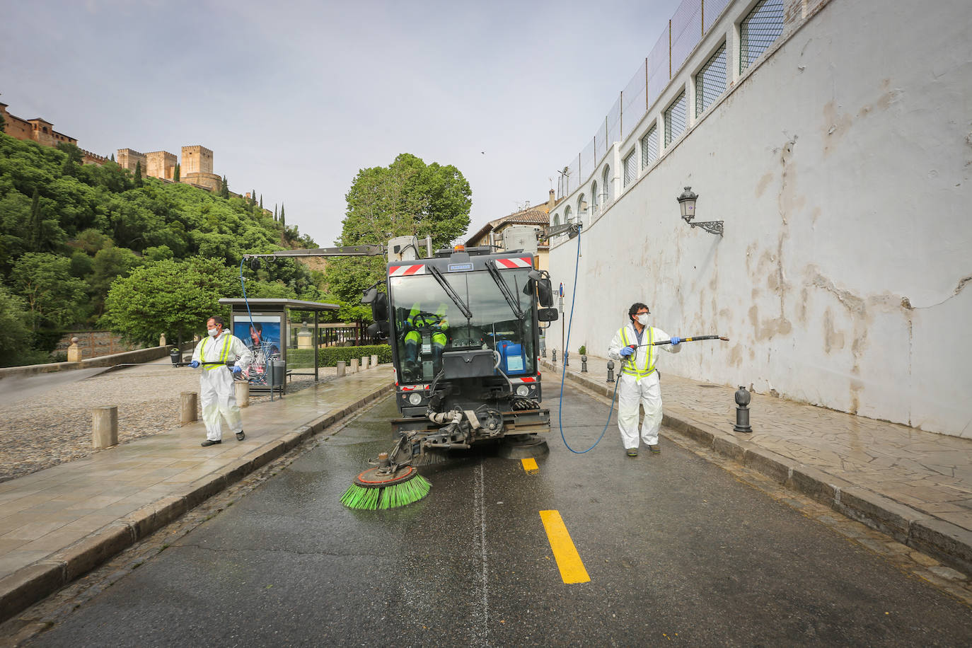 Operarios de Inagra desinfectan el Paseo de los Tristes, con la Alhambra como telón de fondo.