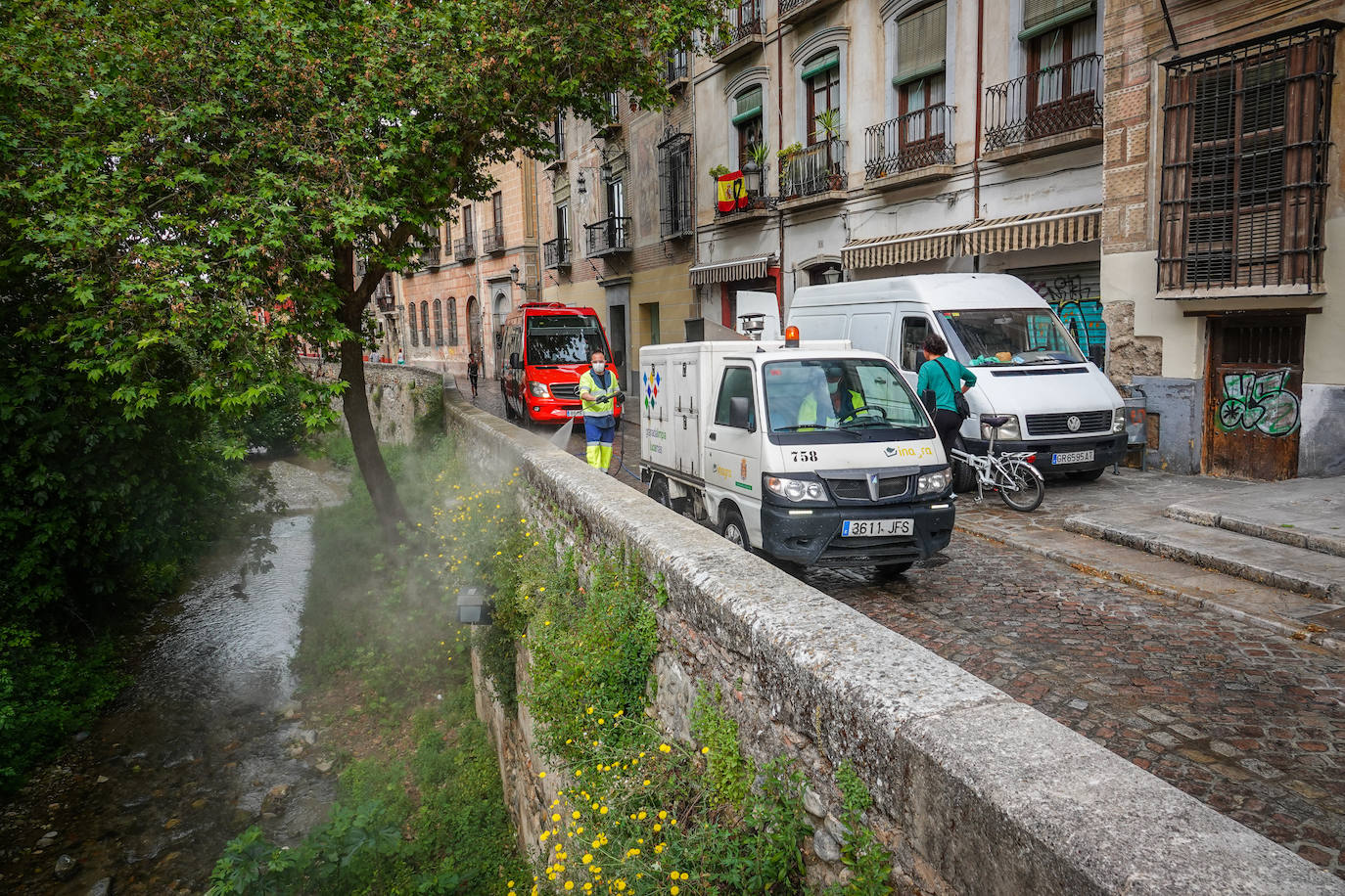 Operarios de Inagra desinfectan el Paseo de los Tristes, con la Alhambra como telón de fondo.