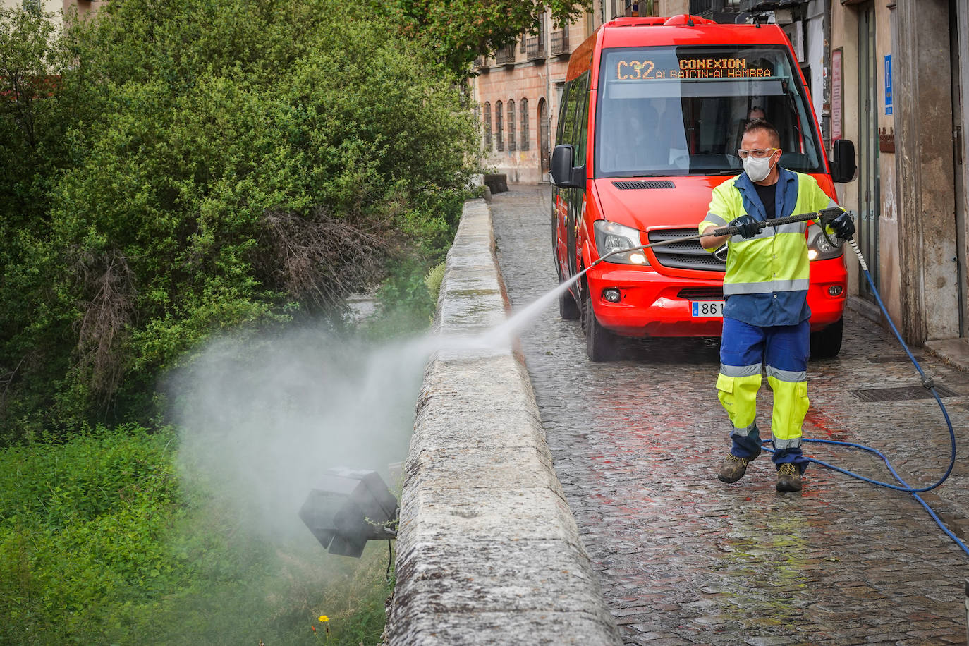Operarios de Inagra desinfectan el Paseo de los Tristes, con la Alhambra como telón de fondo.