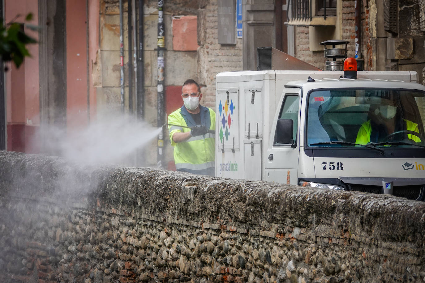 Operarios de Inagra desinfectan el Paseo de los Tristes, con la Alhambra como telón de fondo.
