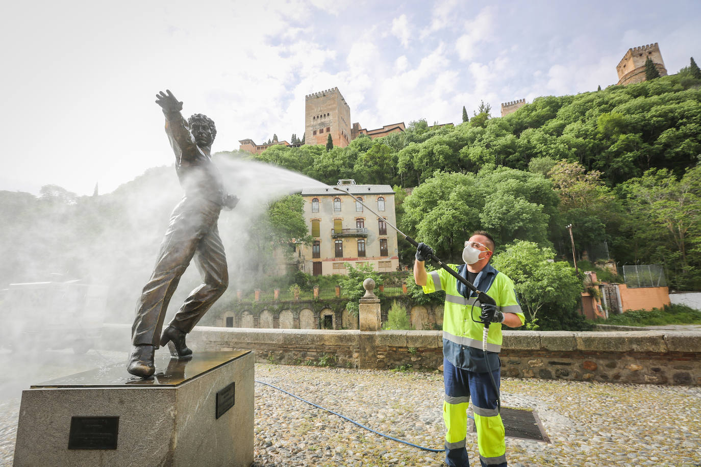Operarios de Inagra desinfectan el Paseo de los Tristes, con la Alhambra como telón de fondo.