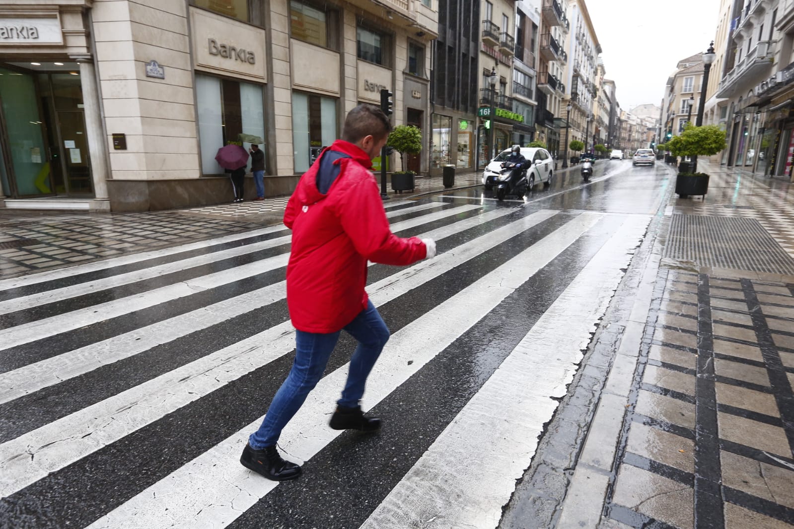 El agua que está cayendo sobre a capital provoca que los granadinos que salen a la calle lo hagan protegidos