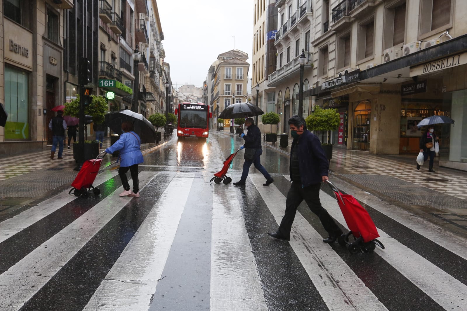El agua que está cayendo sobre a capital provoca que los granadinos que salen a la calle lo hagan protegidos