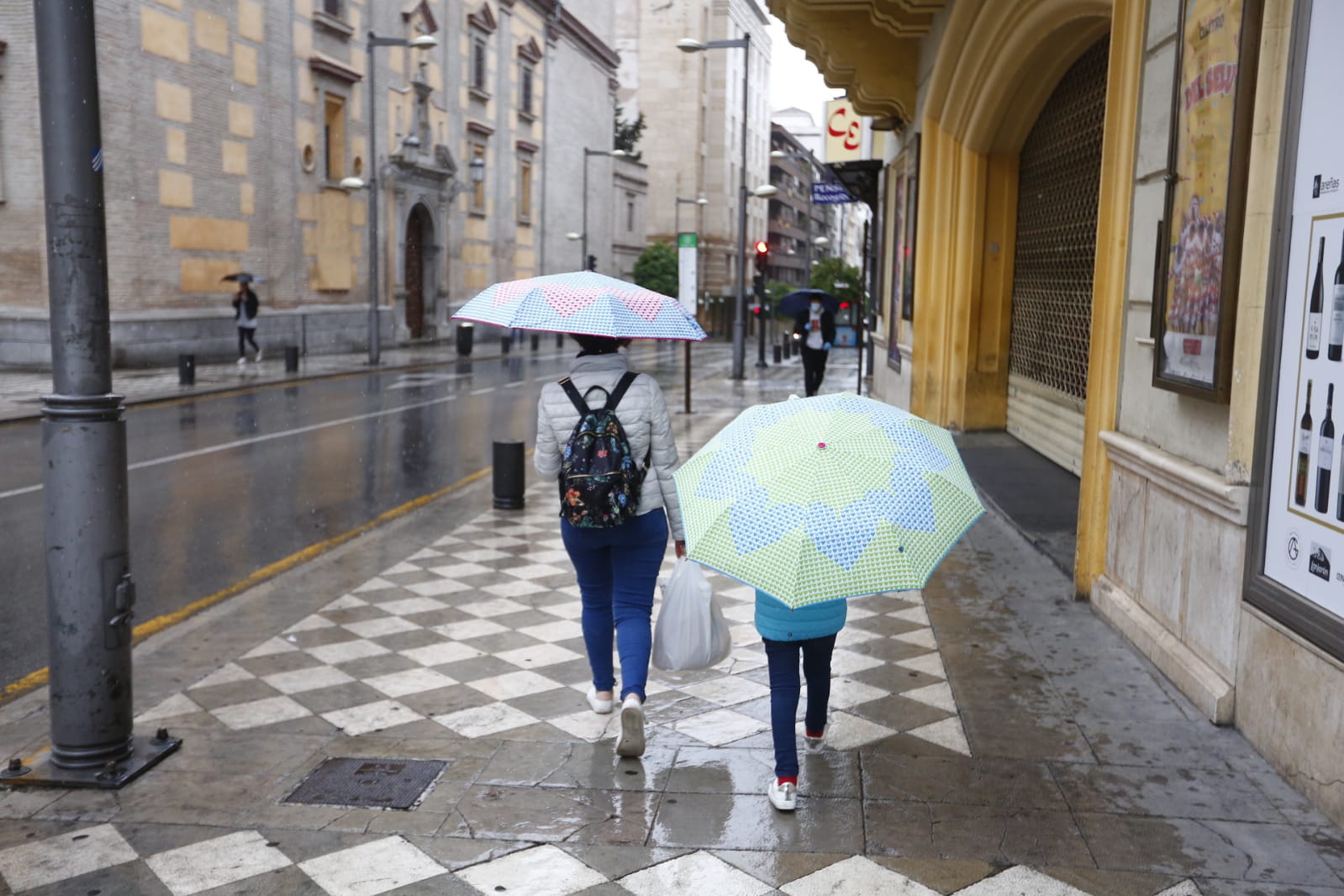 El agua que está cayendo sobre a capital provoca que los granadinos que salen a la calle lo hagan protegidos
