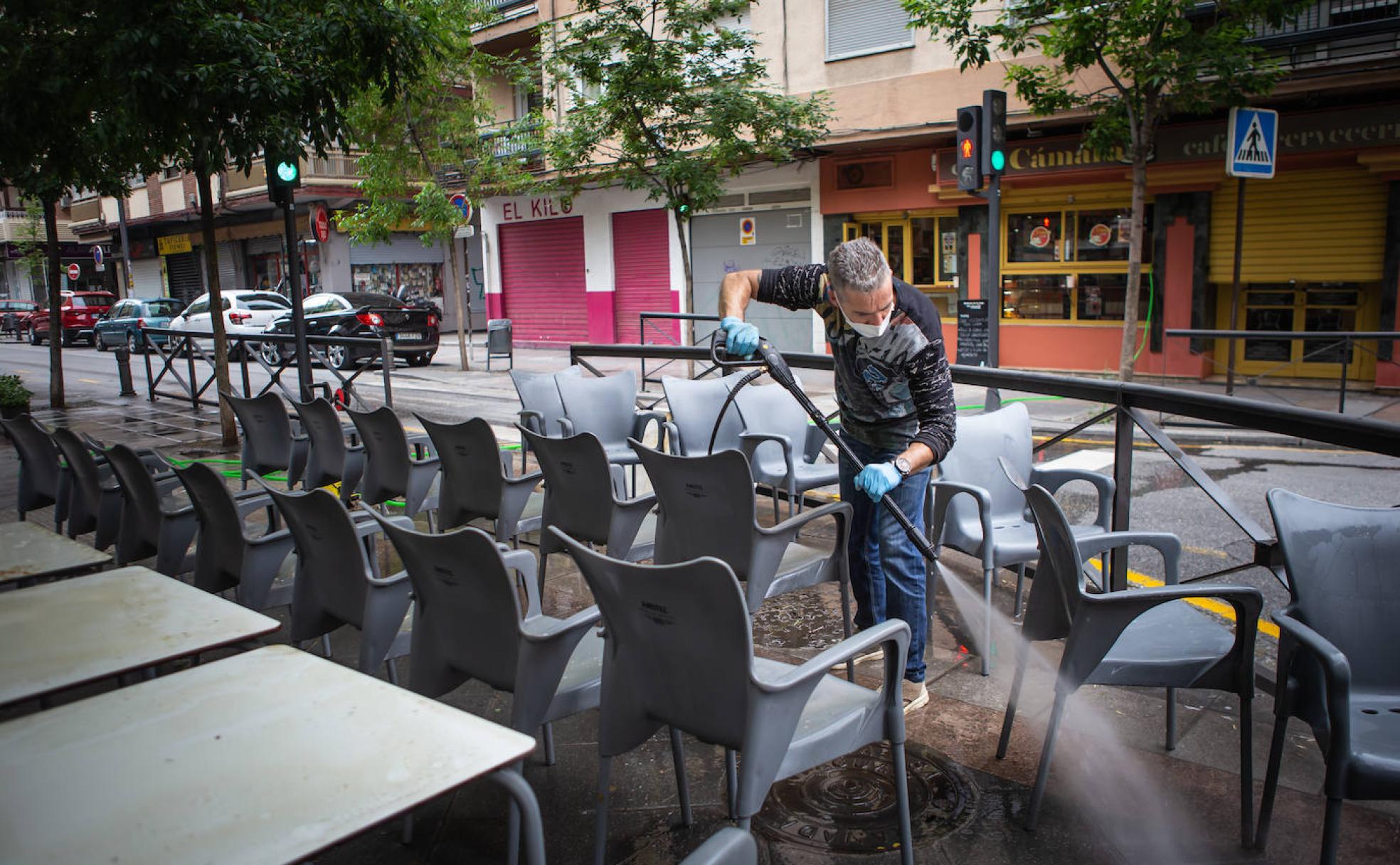 Sergio se emplea a fondo en la limpieza y desinfección de las mesas de su bar, en la calle Pedro Antonio de Alarcón, para la reapertura de la terraza el lunes.