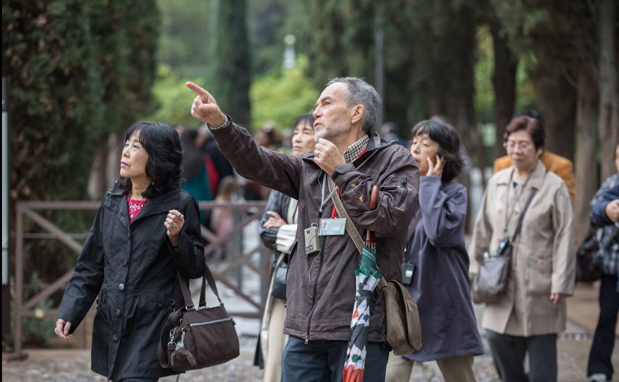 Un guía turístico explica la Alhambra a visitantes extranjeros, antes del coronavirus.