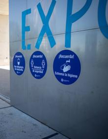 Imagen secundaria 2 - Arriba, dispensador de hidrogel. Abajo, sillas numeradas y localizadas con códigos QR, y señalización en pared.