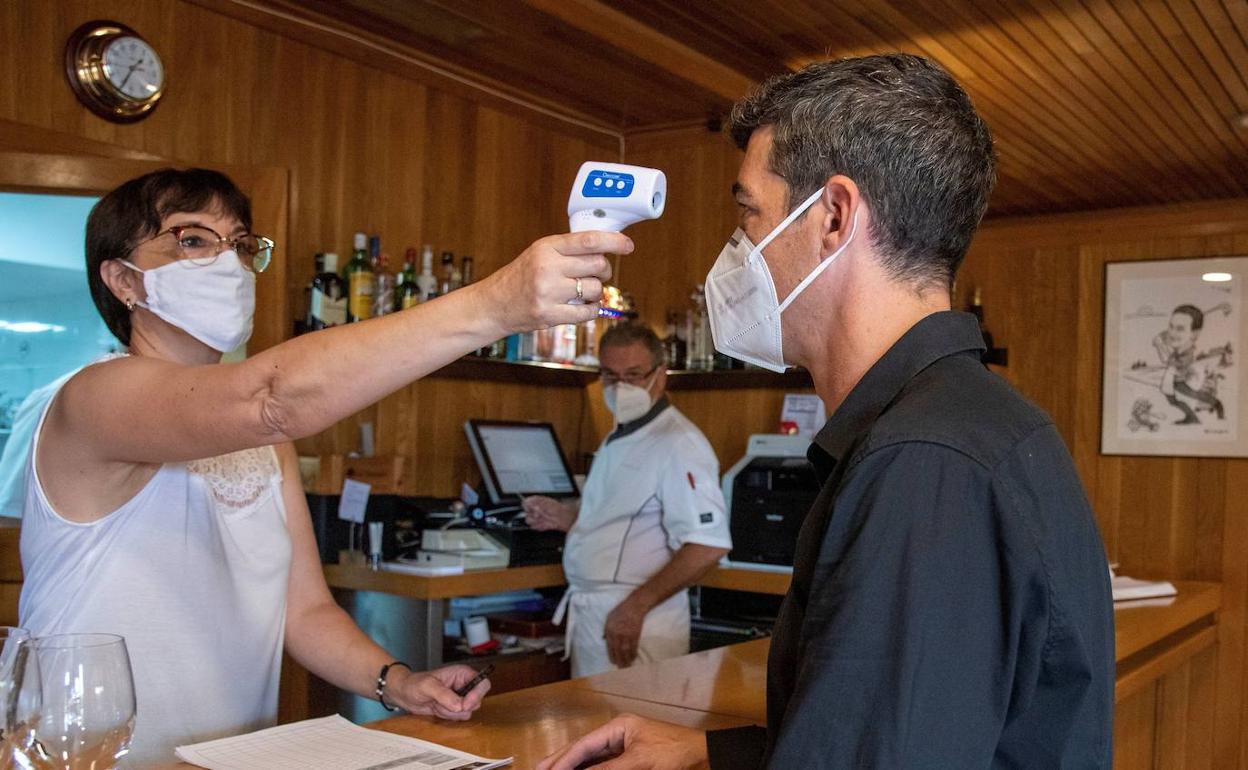Una trabajadora de un restaurante de Lleida toma la temperatura a un cliente, antes de la orden de confinamiento.