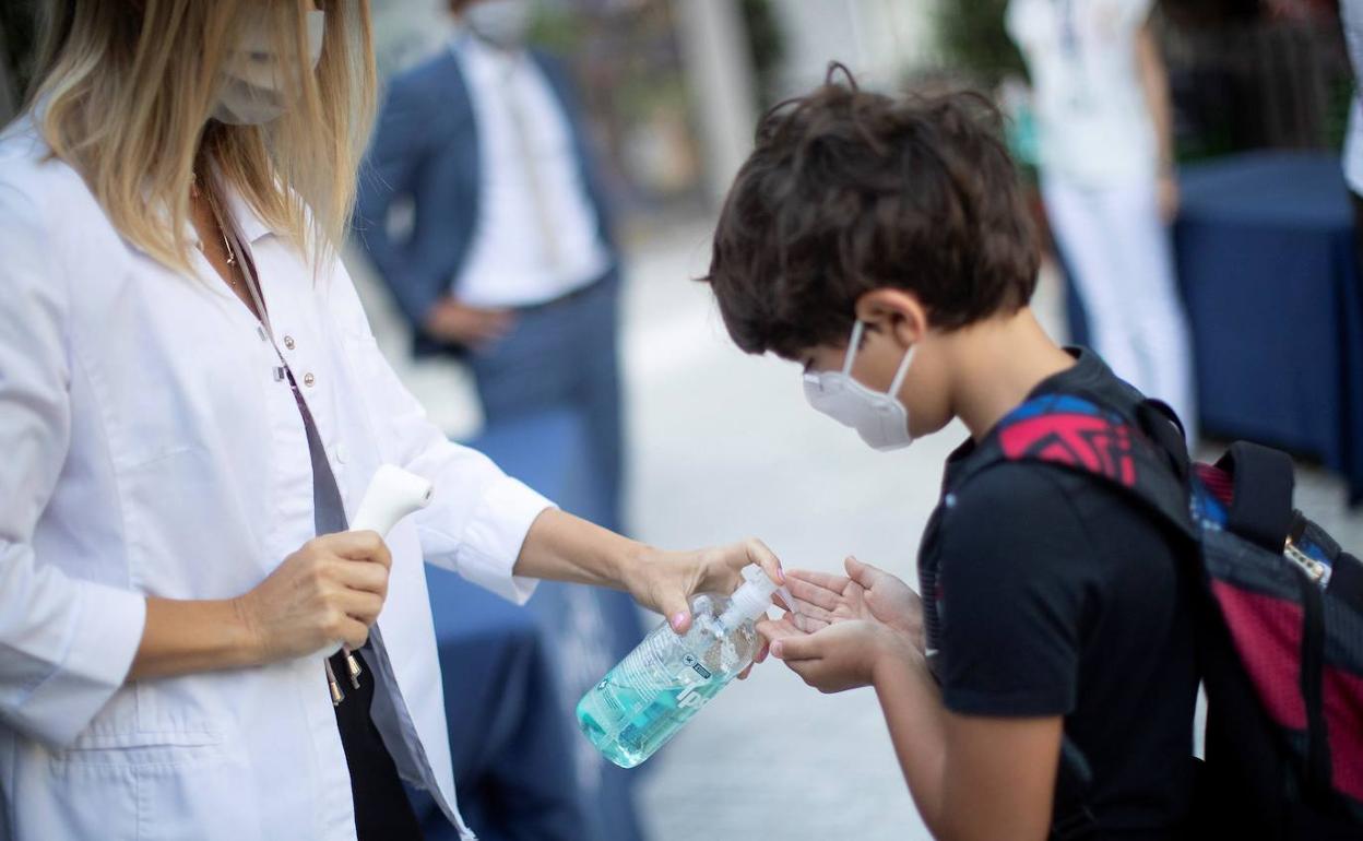 Un niño se desinfecta las manos a la entrada a clase. 