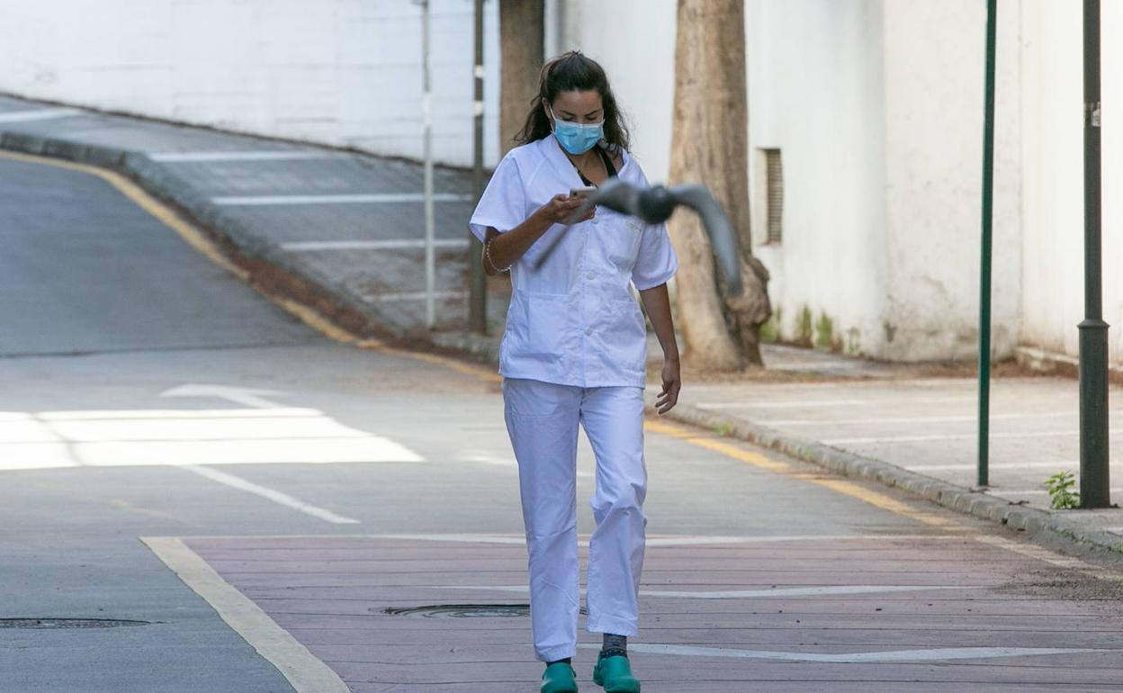Una enfermera camina consultando el móvil.