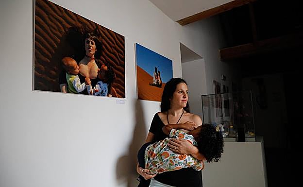 Alicia da de comer a Ayrad junto a la foto que se hizo en el desierto amamantando a sus hijos.