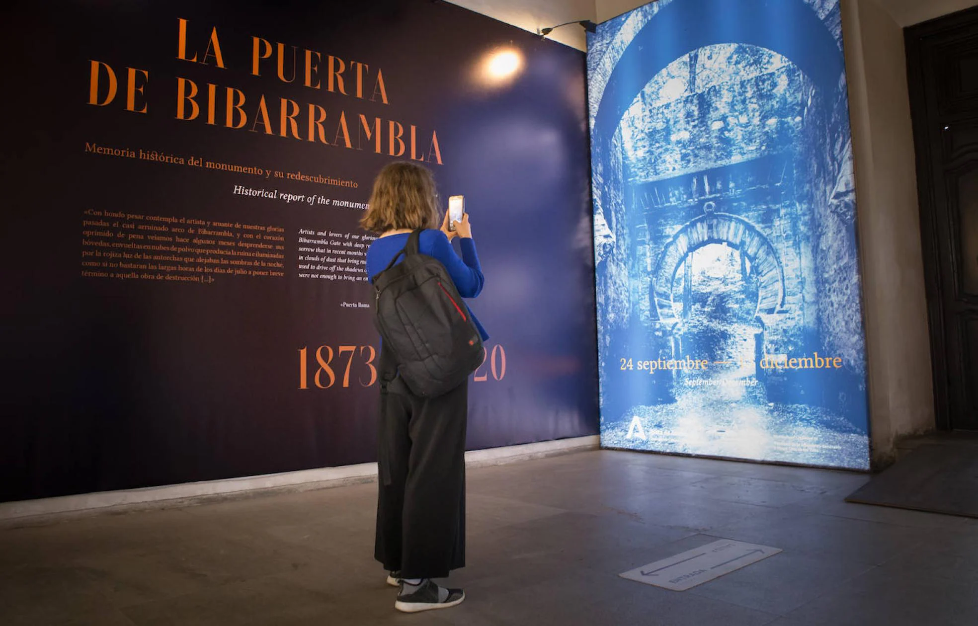 Una mujer inmortaliza la portada de la exposición, que reproduce la Puerta de Bib Rambla que se construyó en el bosque de la Alhambra.