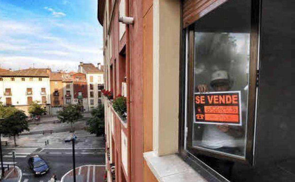 Un hombre coloca un carte de 'Se vende' en una ventana. 