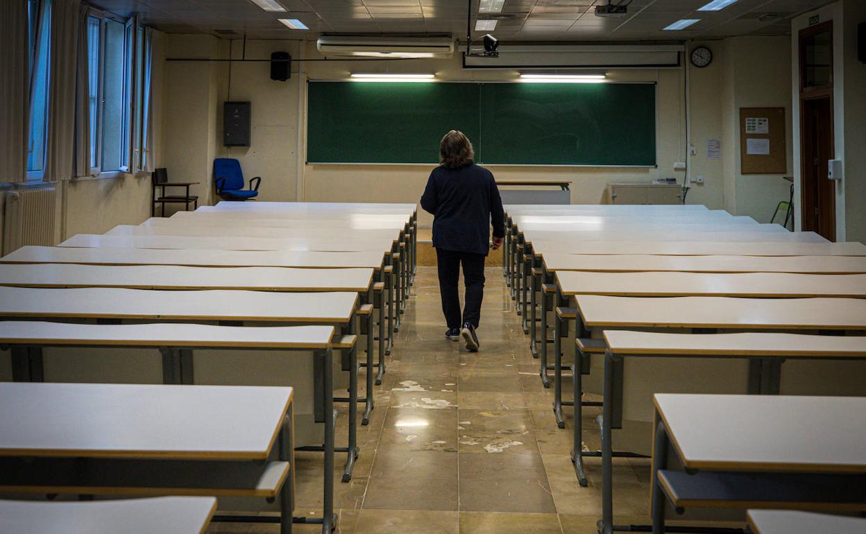 Un profesor camina por un aula sin alumnos de la Facultad de Ciencias de la Universidad de Granada.