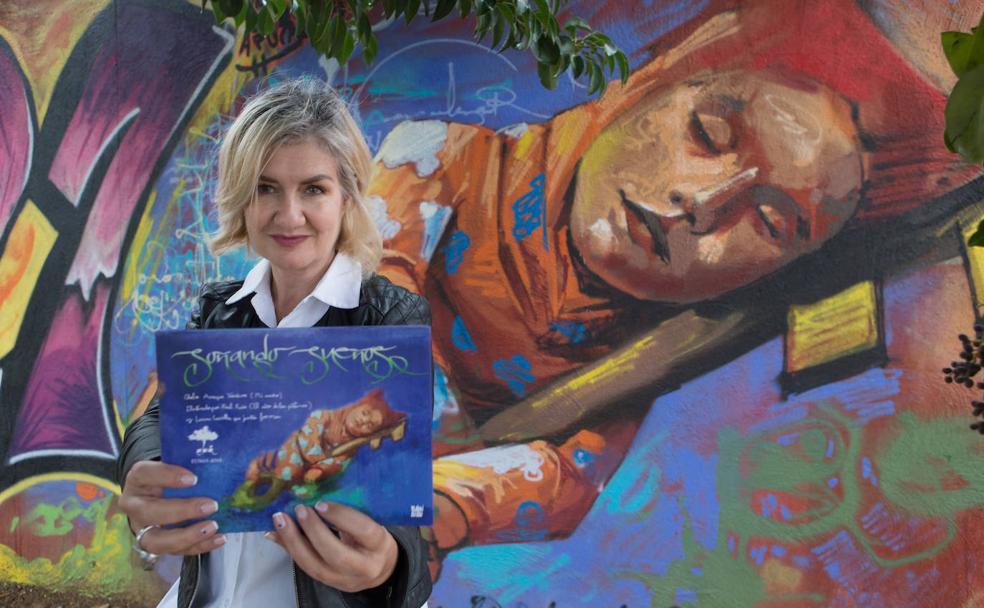 Chelo enseña la portada del cuento ilustrado con un dibujo reproducido en forma de grafiti a la entrada de Purchil. 