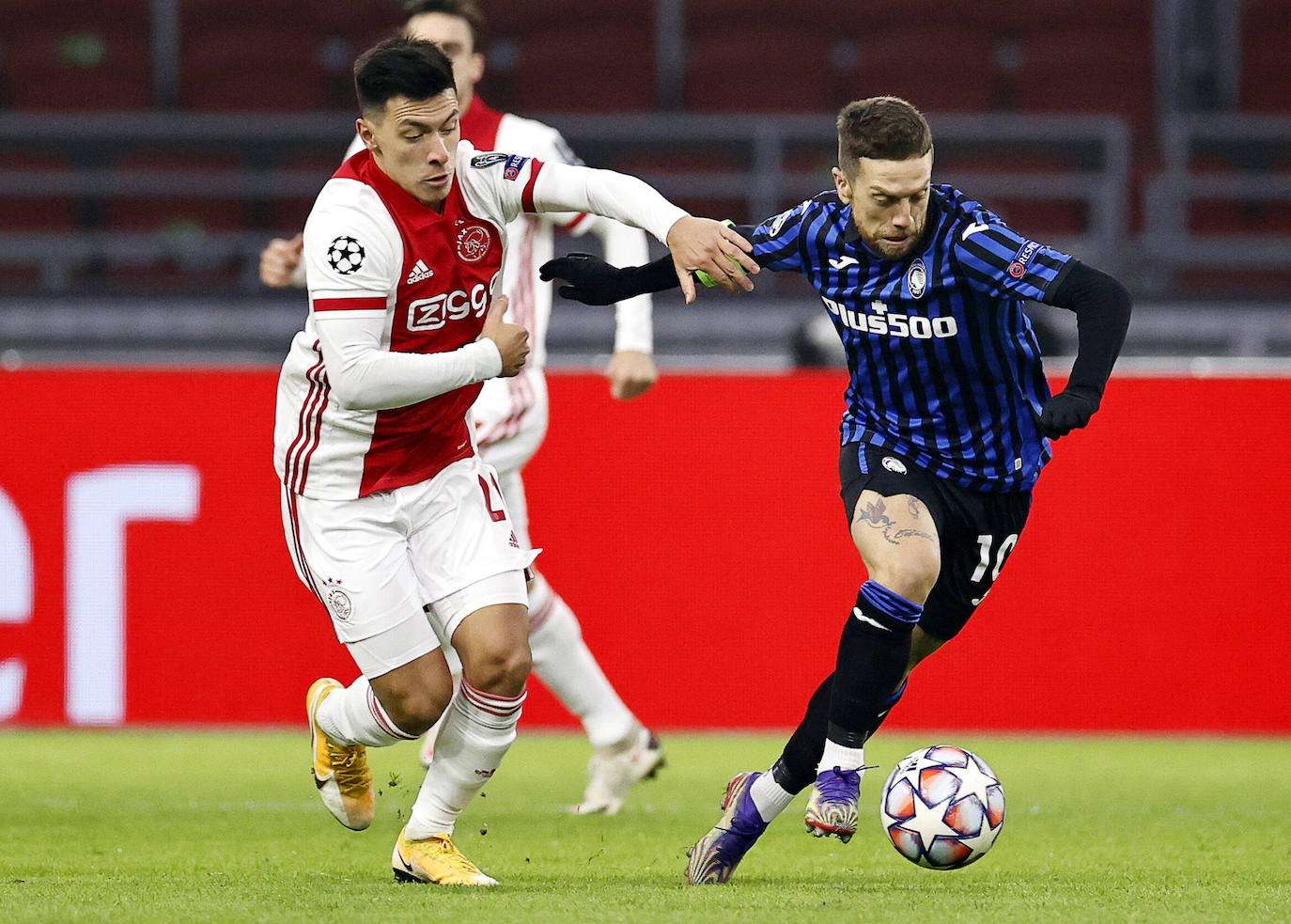 LUn defensa del Ajax trata de frentar al Papu Gómez. 