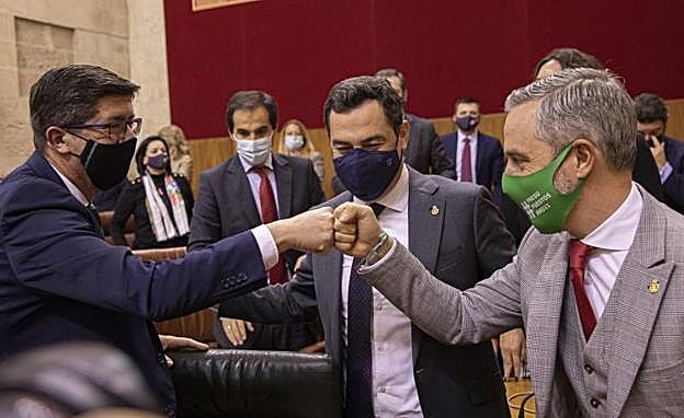 El vicepresidente Juan Marìn y el consejero de Hacienda, Juan Bravo, chocan sus puños en presencia del presidente andaluz Juanma Moreno.