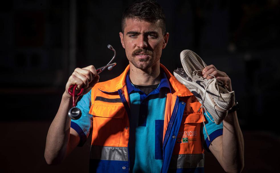 Pablo Sánchez, atleta y enfermero, posa con el uniforme de Urgencias sosteniendo un fonendo con su mano derecha y sus zapatillas de tacos en la izquierda. 