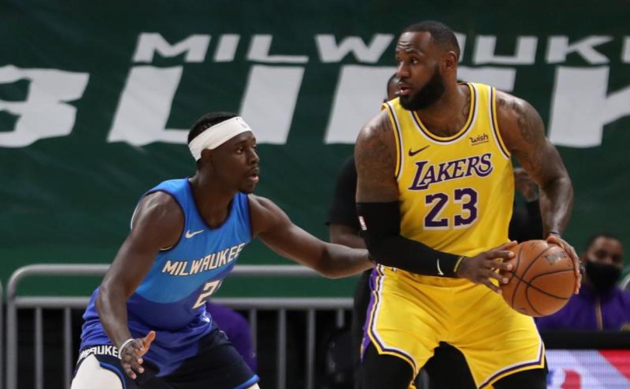 El alero de los Angeles Lakers, LeBron James (23), es defendido por el escolta de los Milwaukee Bucks, Jrue Holiday (21) 